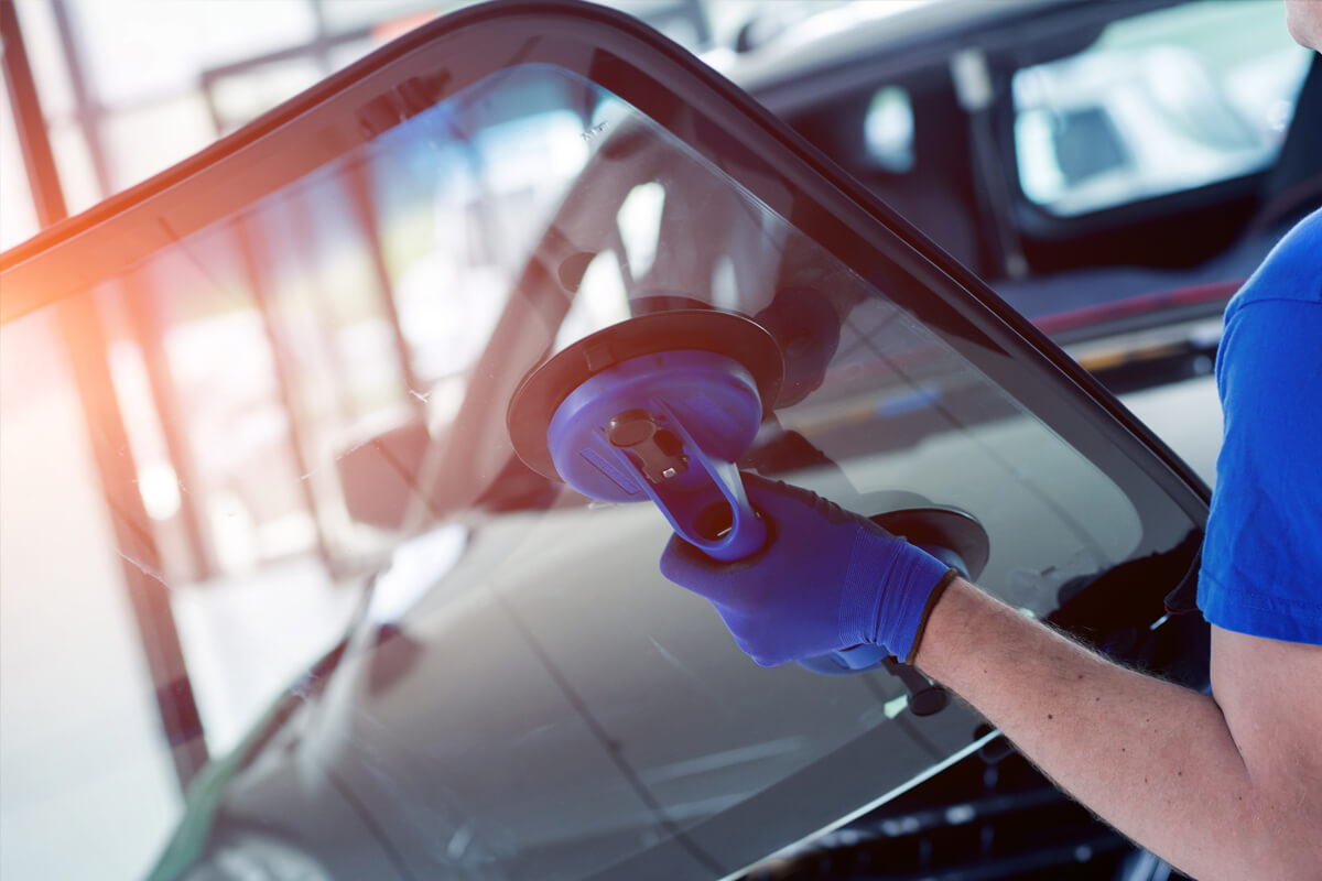 Mitarbeiter wechselt die Autoscheibe am PKW